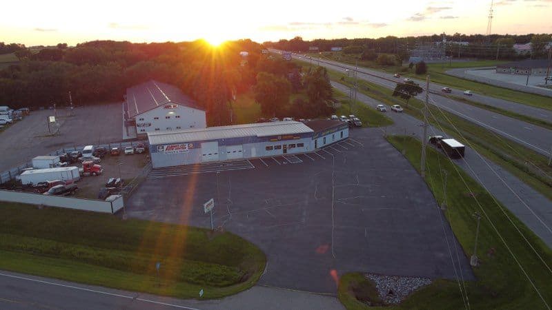 Aerial view of a truck service center at sunset near a highway with trucks parked outside.