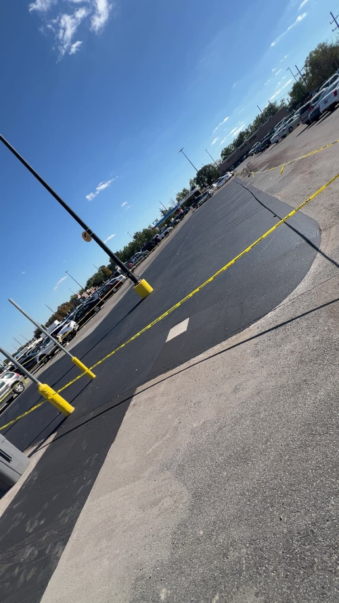 Paved parking lot with yellow barrier tape and clear blue sky in the background.