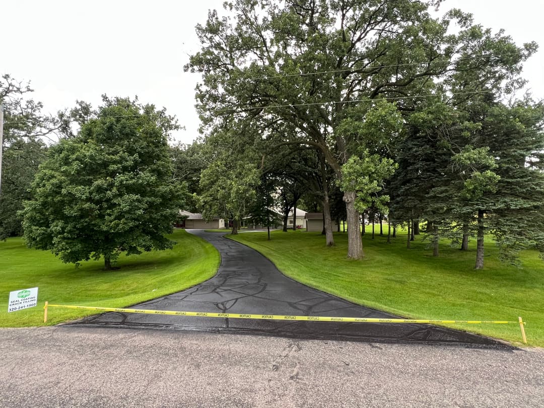Driveway lined with trees leads to a house, marked with caution tape and a sign on the street.