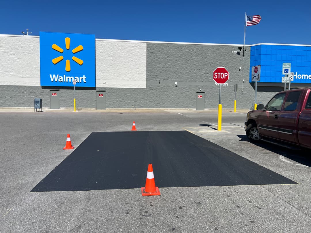 Walmart parking lot with traffic cones marking a construction area and a stop sign nearby.