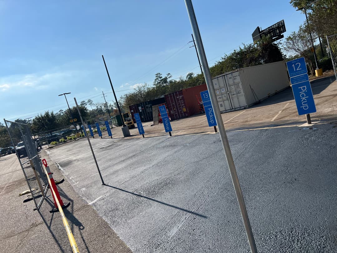Pickup area with numbered signs and containers in a well-lit parking lot.