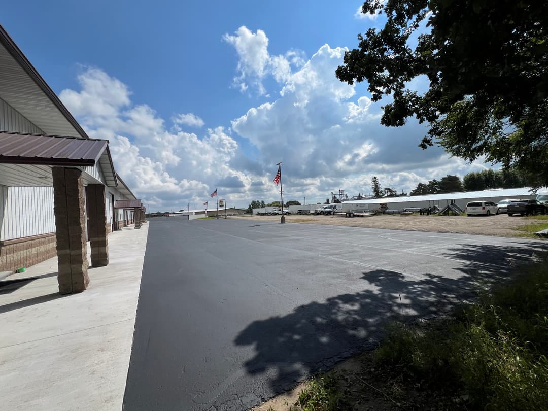 Paved lot with clear skies, American flag, and buildings at a commercial site.