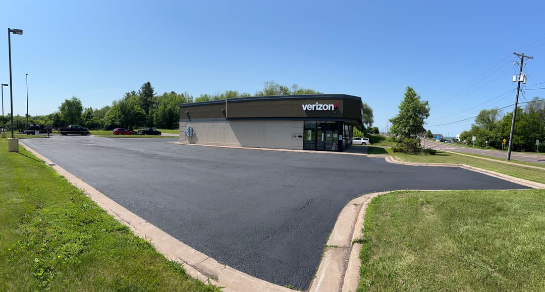 Verizon store exterior with clear sky, green landscaping, and paved parking lot.