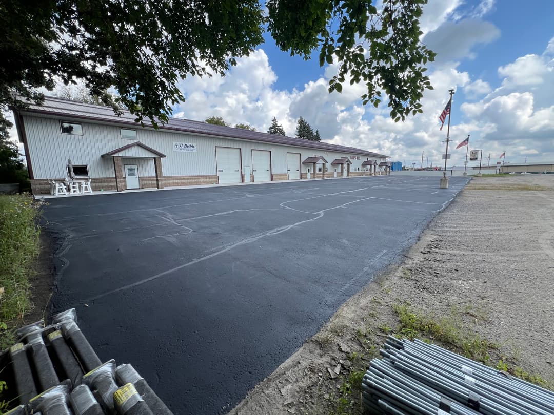 Industrial building with new asphalt parking lot and clear blue sky in the background.