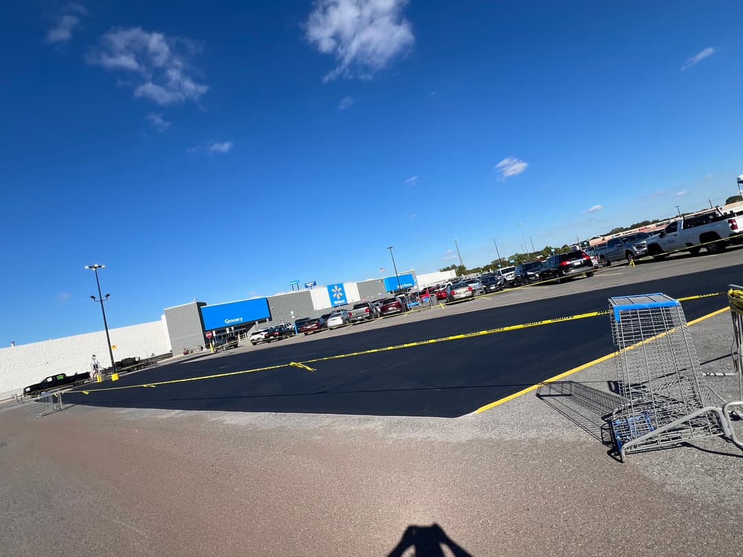 Newly paved parking lot at Walmart with shopping carts and clear blue sky in the background.